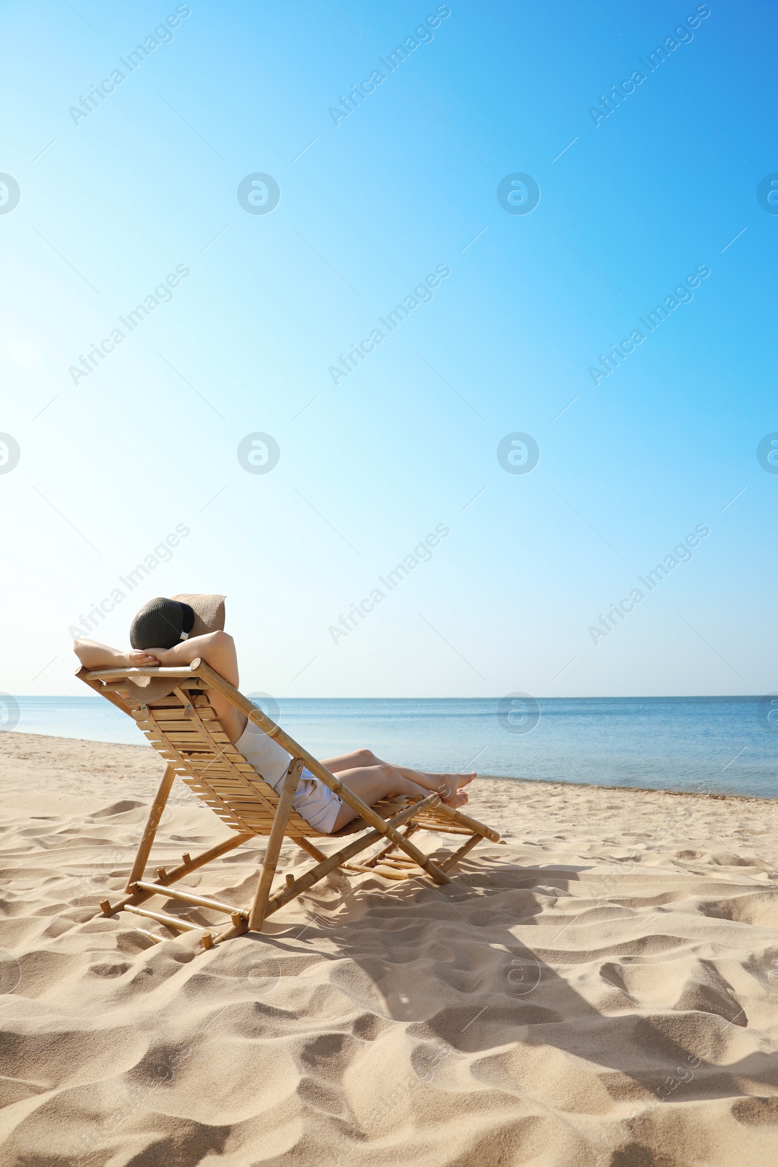 Photo of Young woman relaxing in deck chair on sandy beach