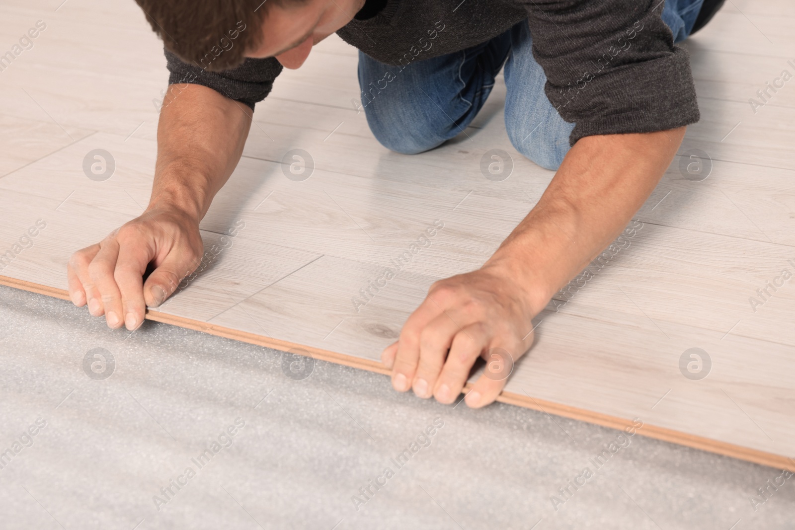 Photo of Professional worker installing new laminate flooring, closeup