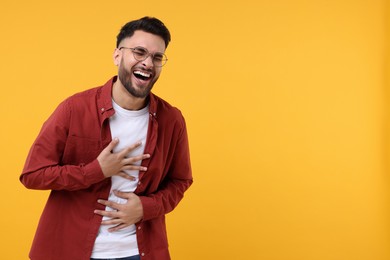 Photo of Handsome young man laughing on yellow background, space for text