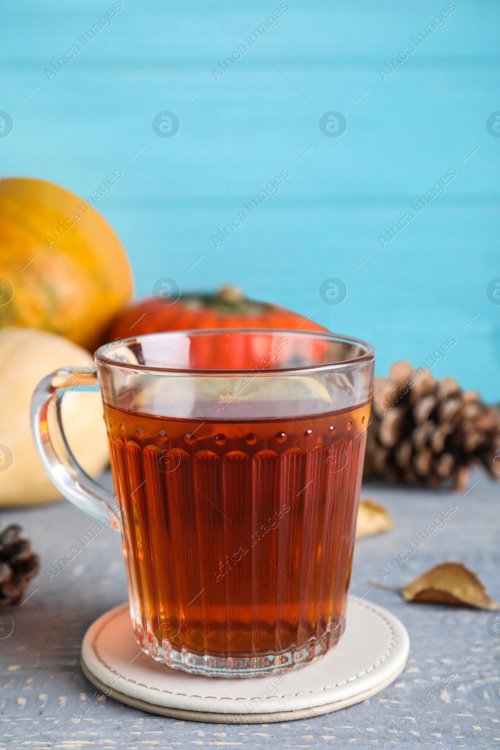 Photo of Cup of hot drink on grey wooden table against blue background. Cozy autumn atmosphere