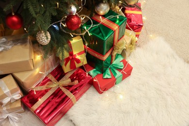 Decorated Christmas tree, beautiful gift boxes and festive lights on carpet