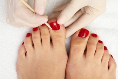 Pedicurist working with client`s toenails in beauty salon, top view