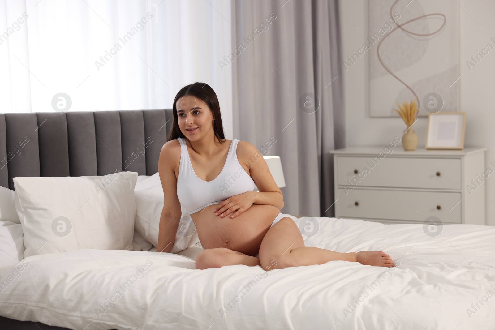 Photo of Beautiful pregnant woman in stylish comfortable underwear on bed at home