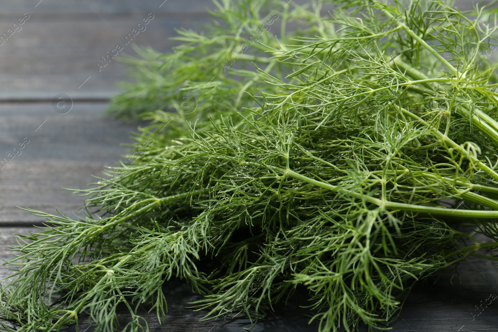 Photo of Fresh green dill on grey wooden table, closeup