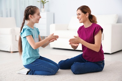 Hearing impaired mother and her child talking with help of sign language indoors