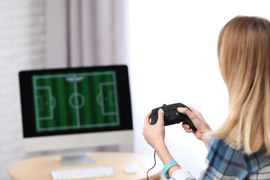 Photo of Young woman playing video game at home