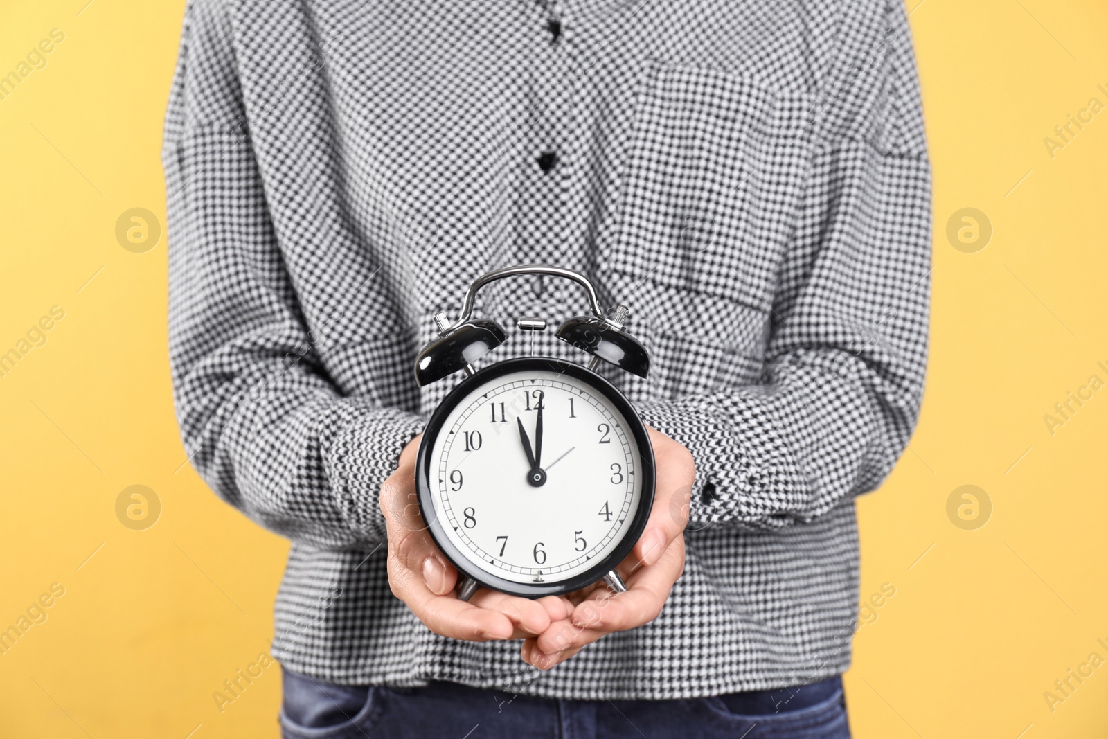 Photo of Young woman holding clock on color background. Time management