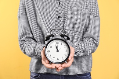 Young woman holding clock on color background. Time management