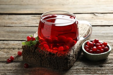 Photo of Delicious cranberry tea and berries on wooden table