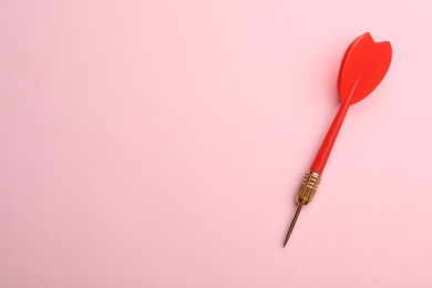 Photo of Red dart arrow on pink background, top view with space for text