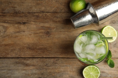Photo of Delicious mojito and ingredients on wooden table, flat lay. Space for text