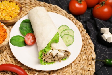 Photo of Delicious tortilla wrap with tuna on wicker mat