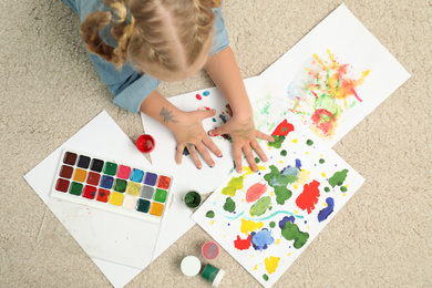Photo of Little child painting with palms on floor, top view