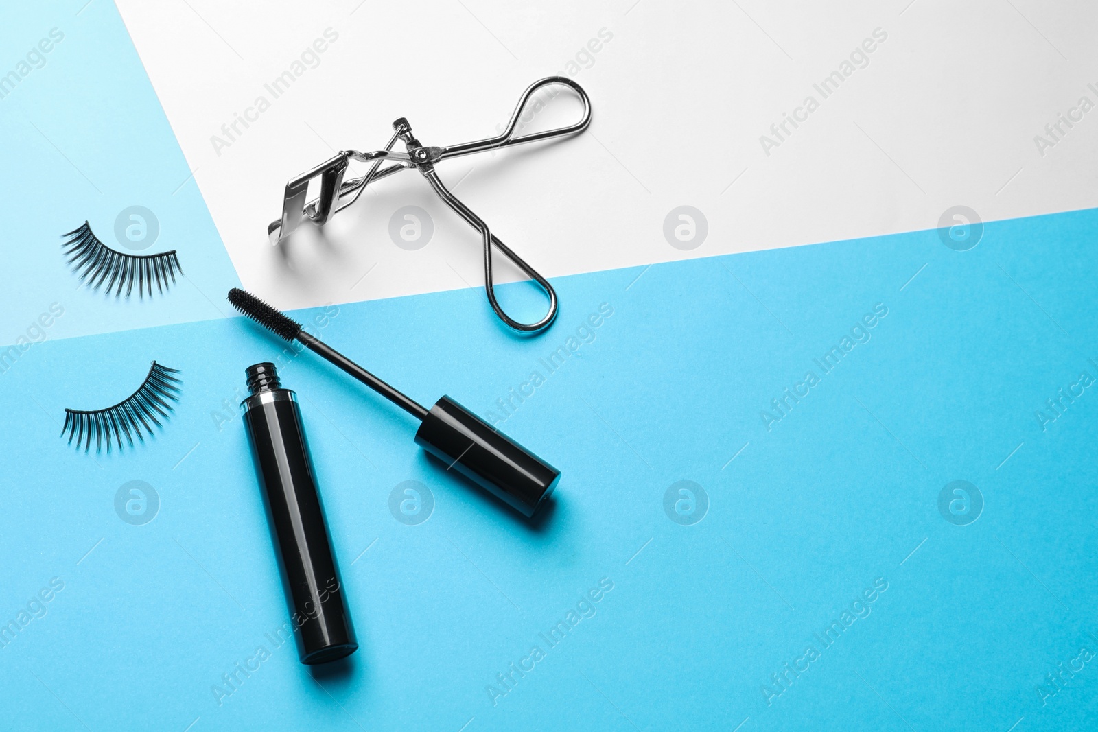 Photo of False eyelashes, curler and mascara on color background, space for text