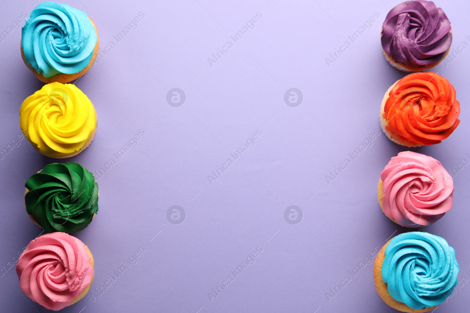 Photo of Delicious cupcakes with bright cream on violet background, flat lay. Space for text