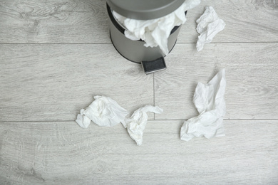 Used paper tissues and trash can on wooden floor, above view