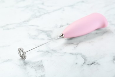 Pink milk frother wand on white marble table