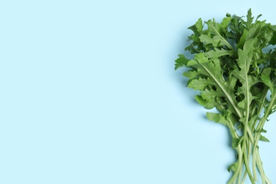 Fresh arugula on light blue background, flat lay. Space for text