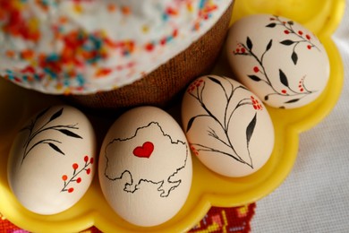 Photo of Easter kulich and decorated eggs on cloth, top view