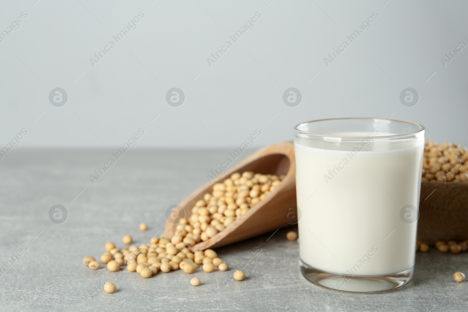 Photo of Glass with fresh soy milk and grains on grey table. Space for text