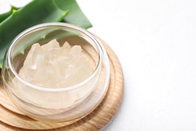 Aloe vera gel and slices of plant on white background, closeup. Space for text