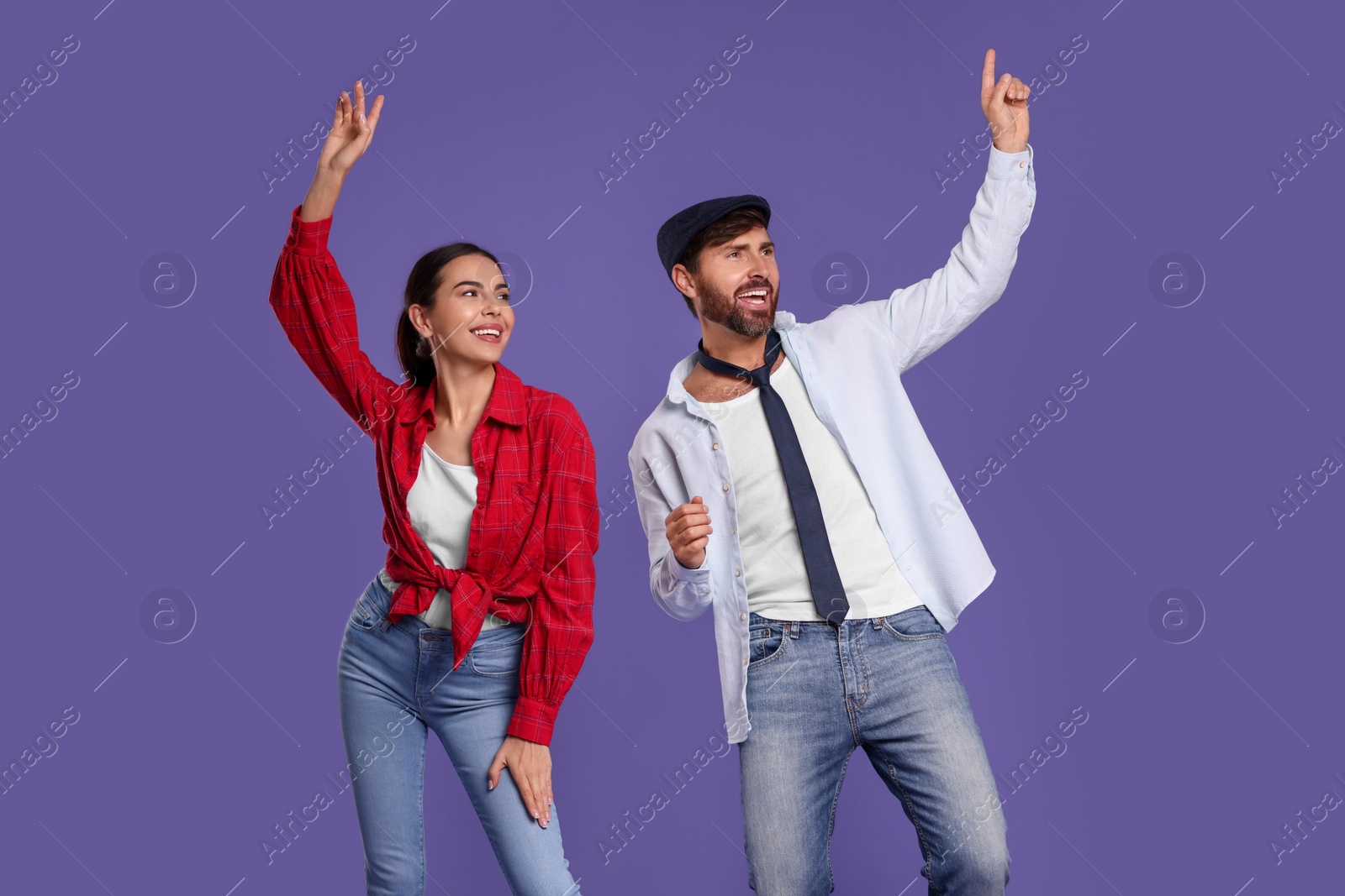 Photo of Happy couple dancing together on violet background