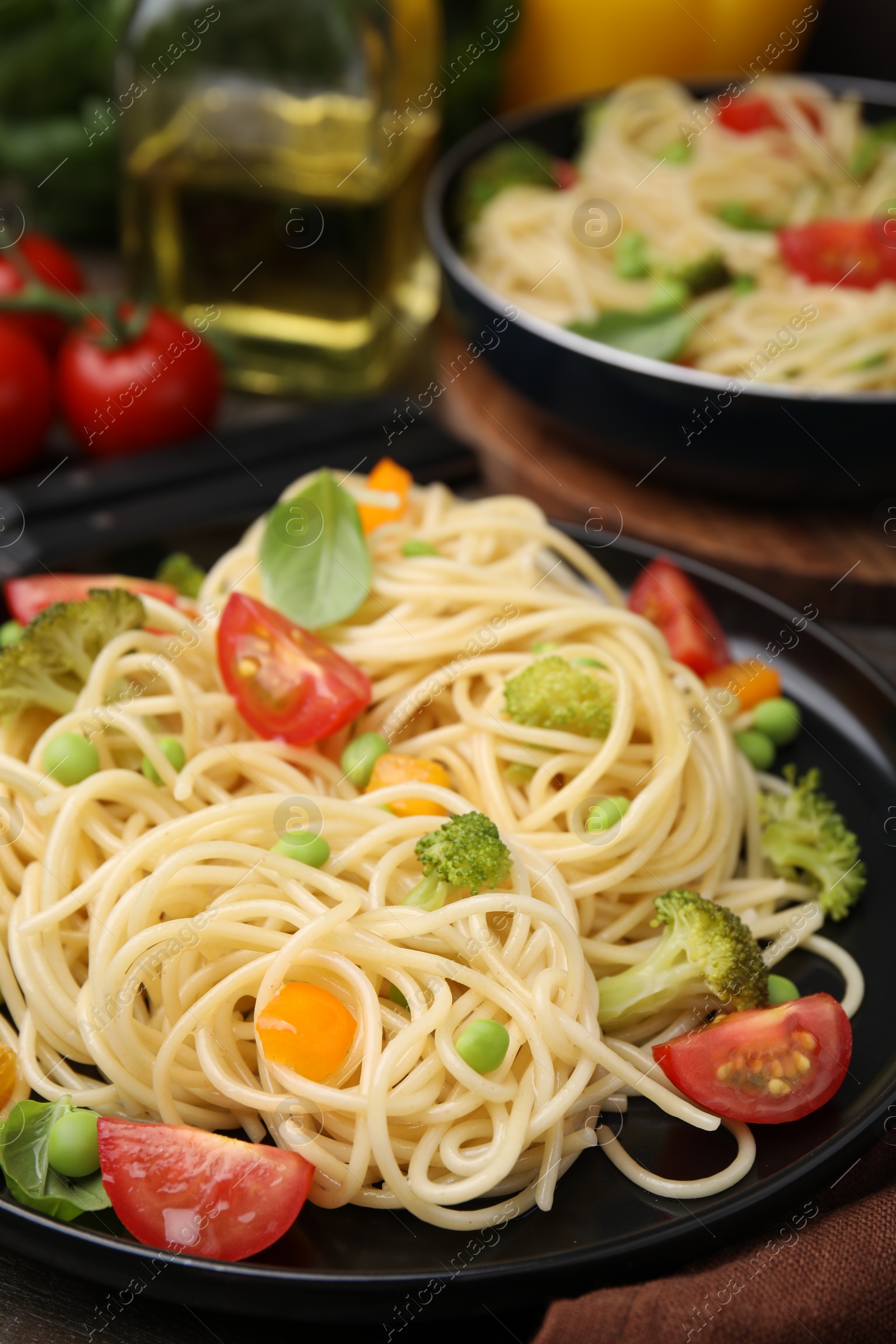 Photo of Plate of delicious pasta primavera and ingredients on table, closeup