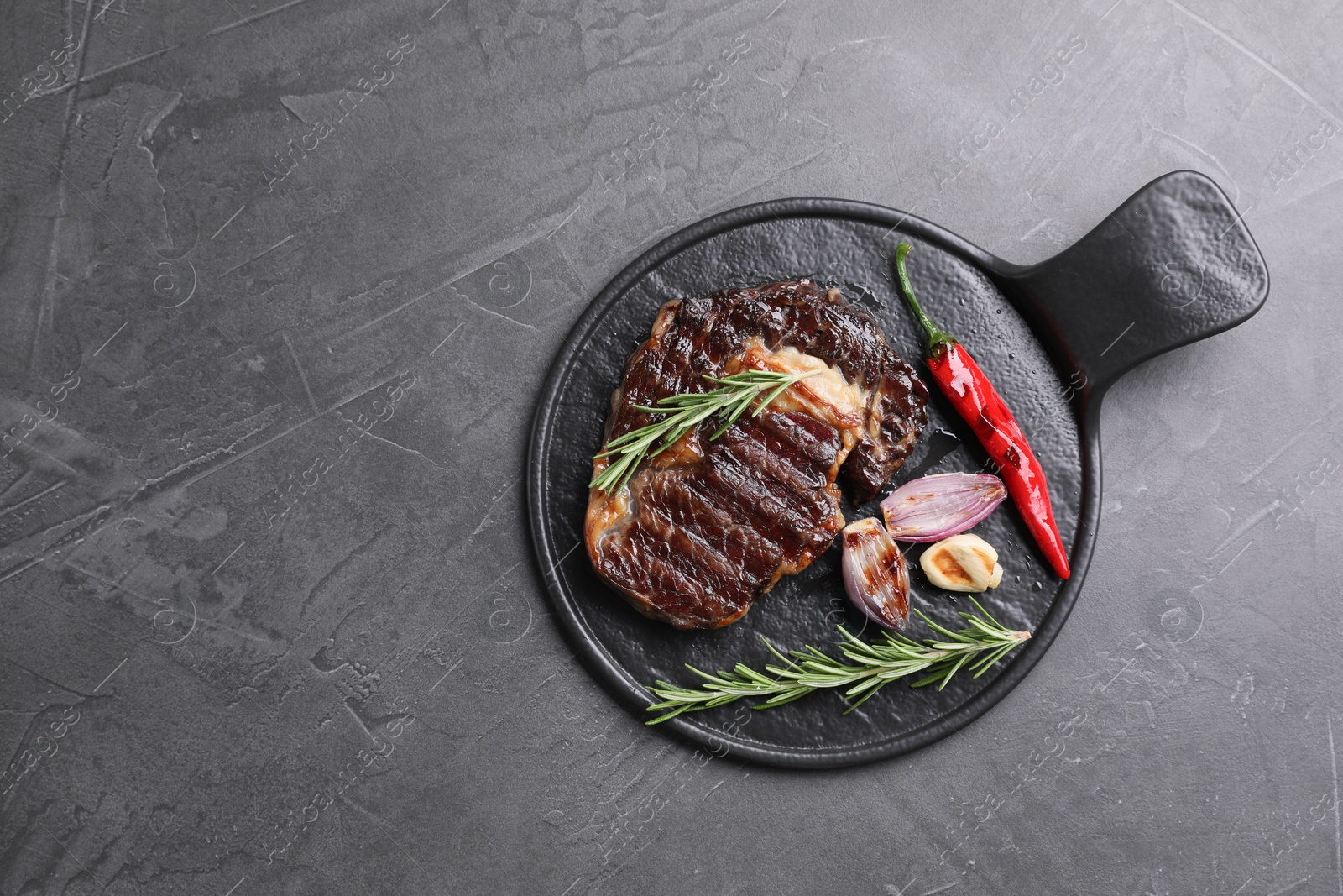 Photo of Delicious grilled beef meat, rosemary and spices on gray textured table, top view. Space for text