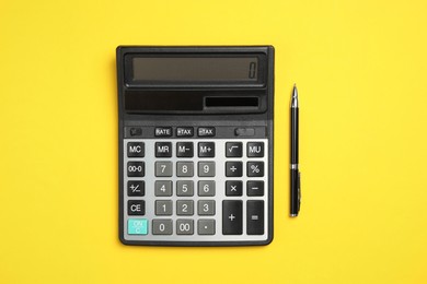 Calculator and pen on yellow background, flat lay