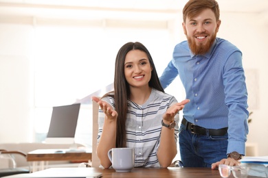 Photo of Happy young couple looking at camera and using video chat in home office. Space for text