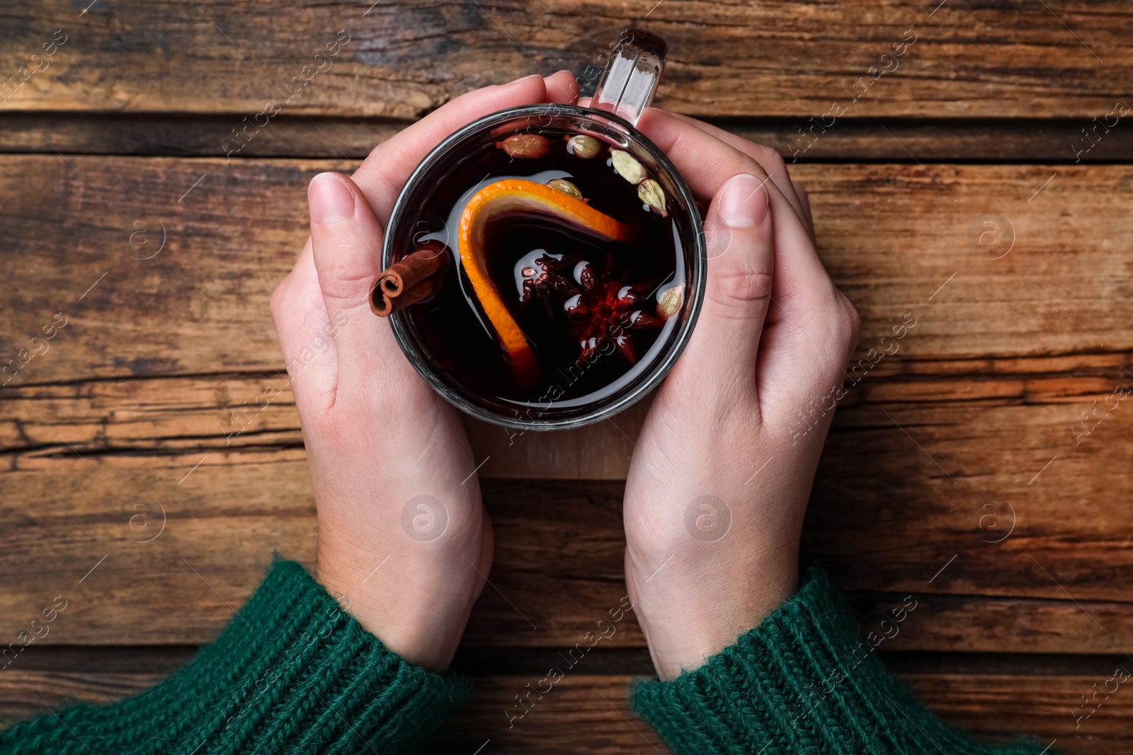 Photo of Woman with cup of mulled wine at wooden table, top view