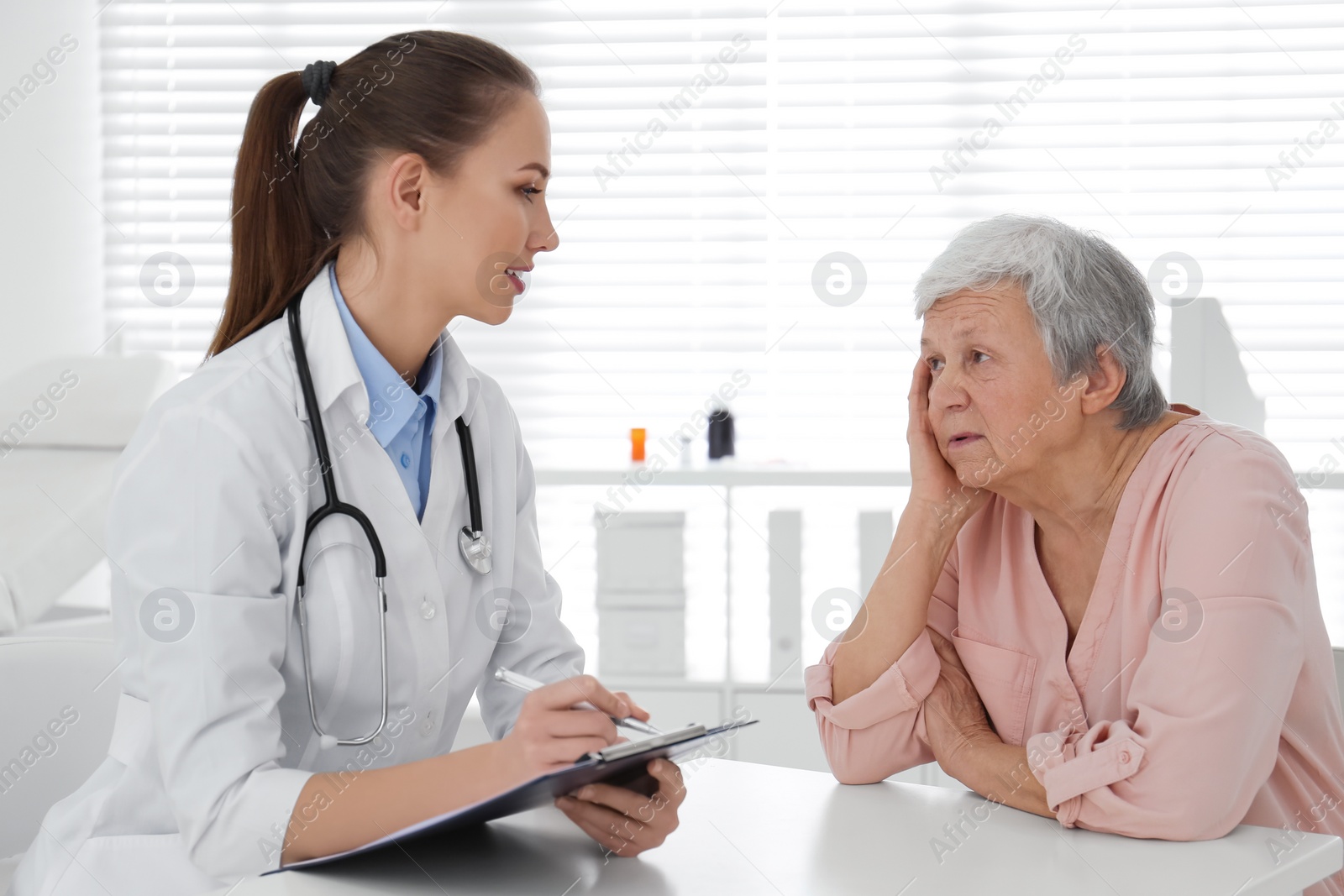 Photo of Doctor examining senior patient in modern office