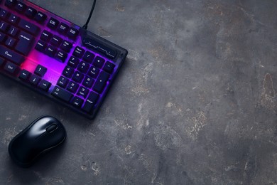 Modern RGB keyboard and mouse on grey table, flat lay. Space for text