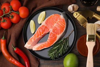 Fresh fish, products and marinade on wooden table, flat lay