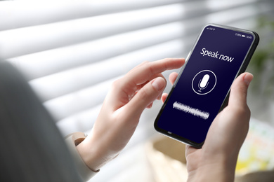 Image of Woman using voice search on smartphone indoors, closeup