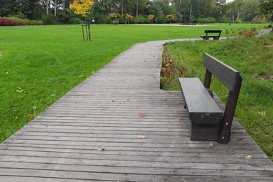 Photo of Wooden bench near pathway in beautiful public city park