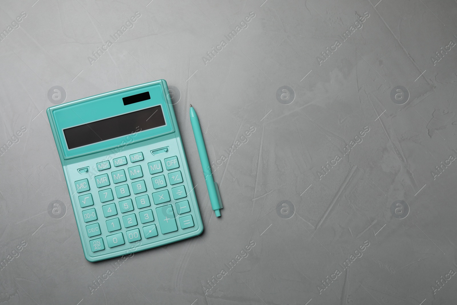 Photo of Calculator and pen on grey table, top view. Space for text