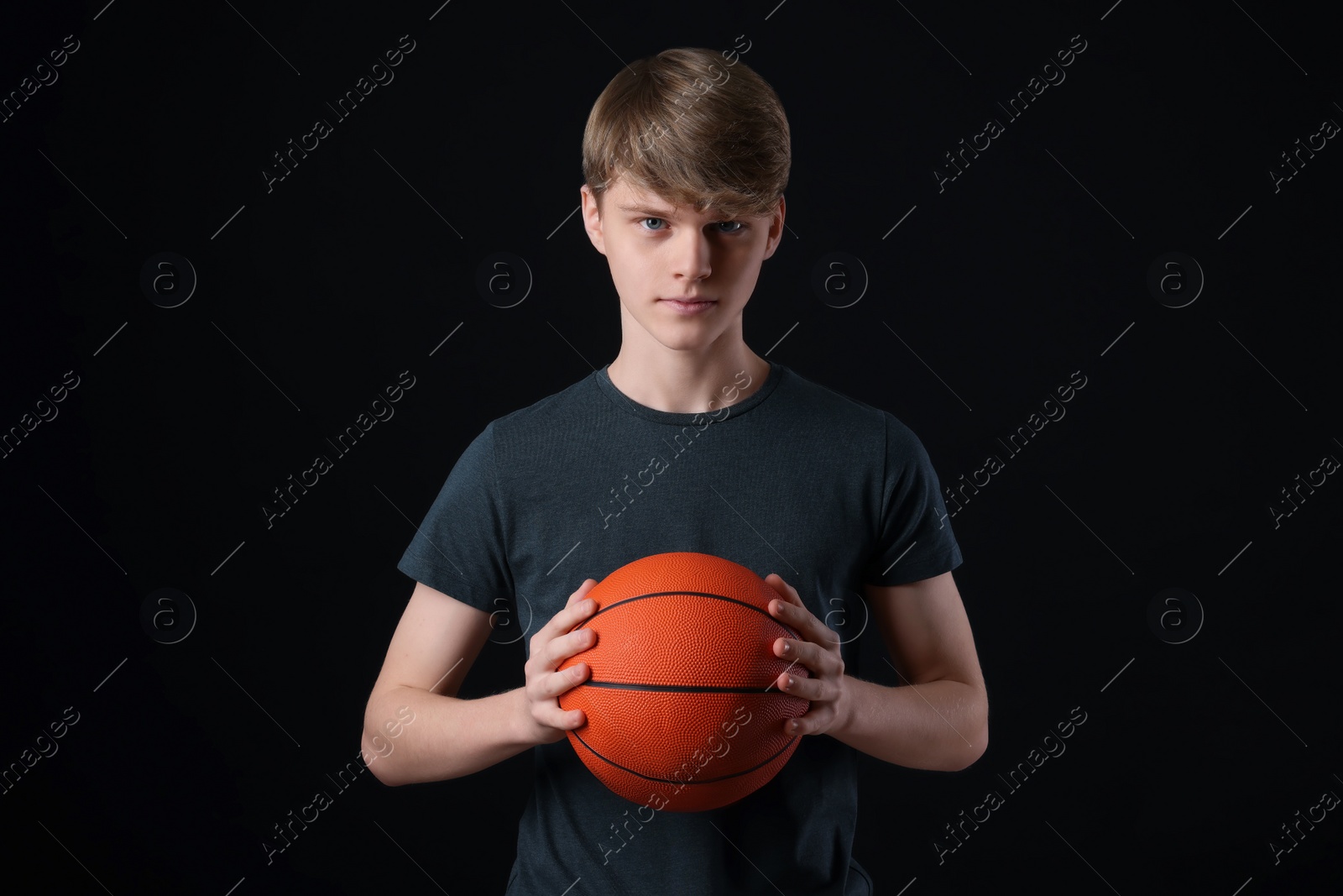 Photo of Teenage boy with basketball ball on black background