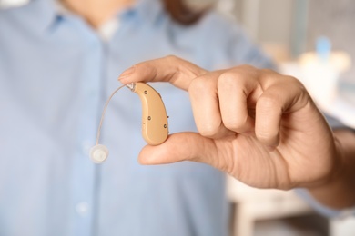 Photo of Woman holding hearing aid, closeup of hand