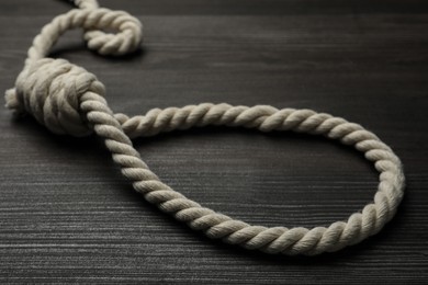 Rope noose on dark wooden table, closeup