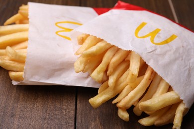 MYKOLAIV, UKRAINE - AUGUST 12, 2021: Two small portions of McDonald's French fries on wooden table, closeup