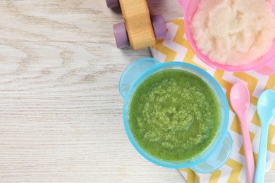 Healthy baby food. Different tasty puree in bowls on white wooden table, flat lay with space for text