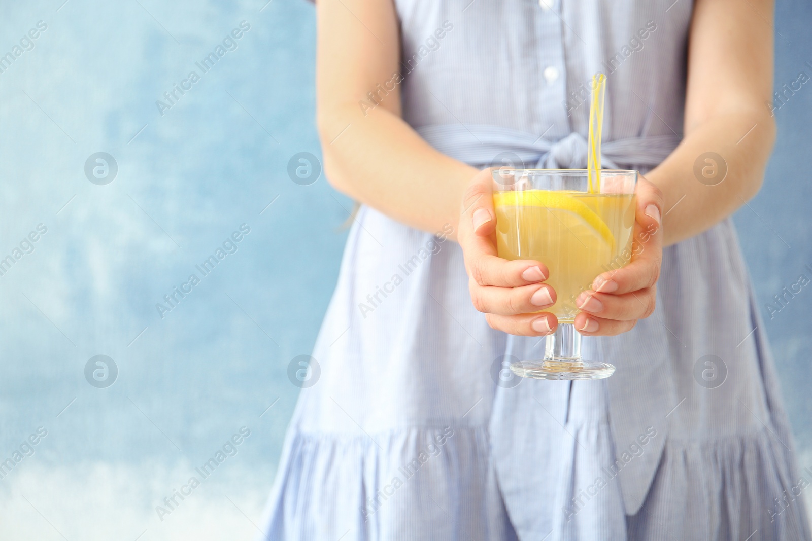 Photo of Young woman holding glass with lemon cocktail against color background