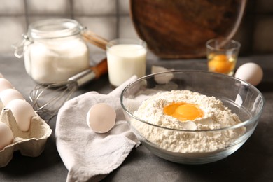 Photo of Making dough. Flour with egg yolk in bowl on grey table, closeup