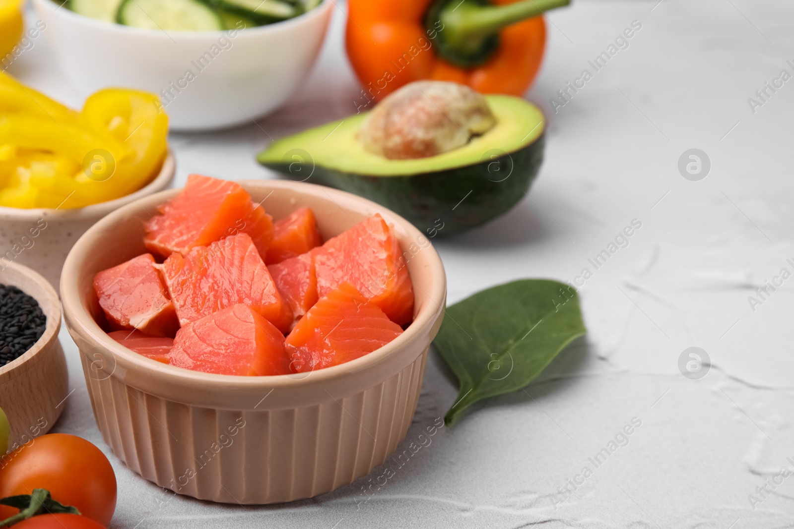 Photo of Ingredients for poke bowl on white textured table, closeup. Space for text