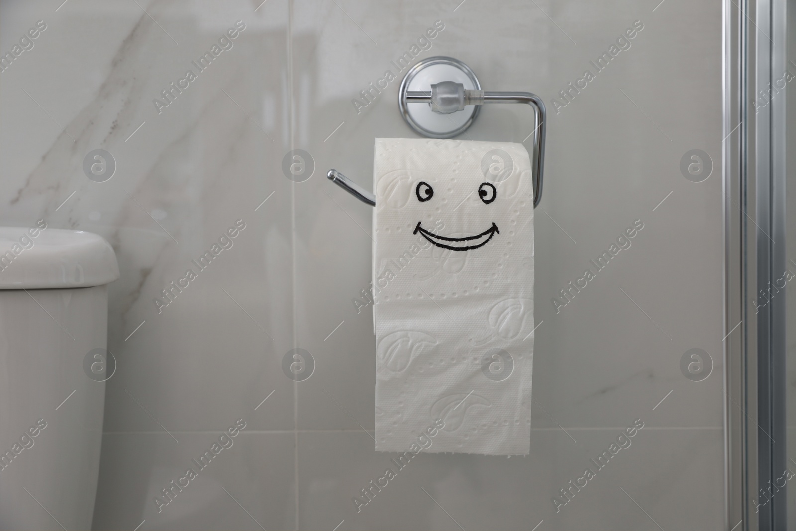 Photo of Paper with drawn funny face near toilet tank in bathroom