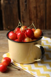 Sweet red cherries in enameled mug on wooden table