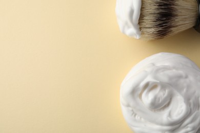 Photo of Brush and shaving foam on beige background, flat lay. Space for text