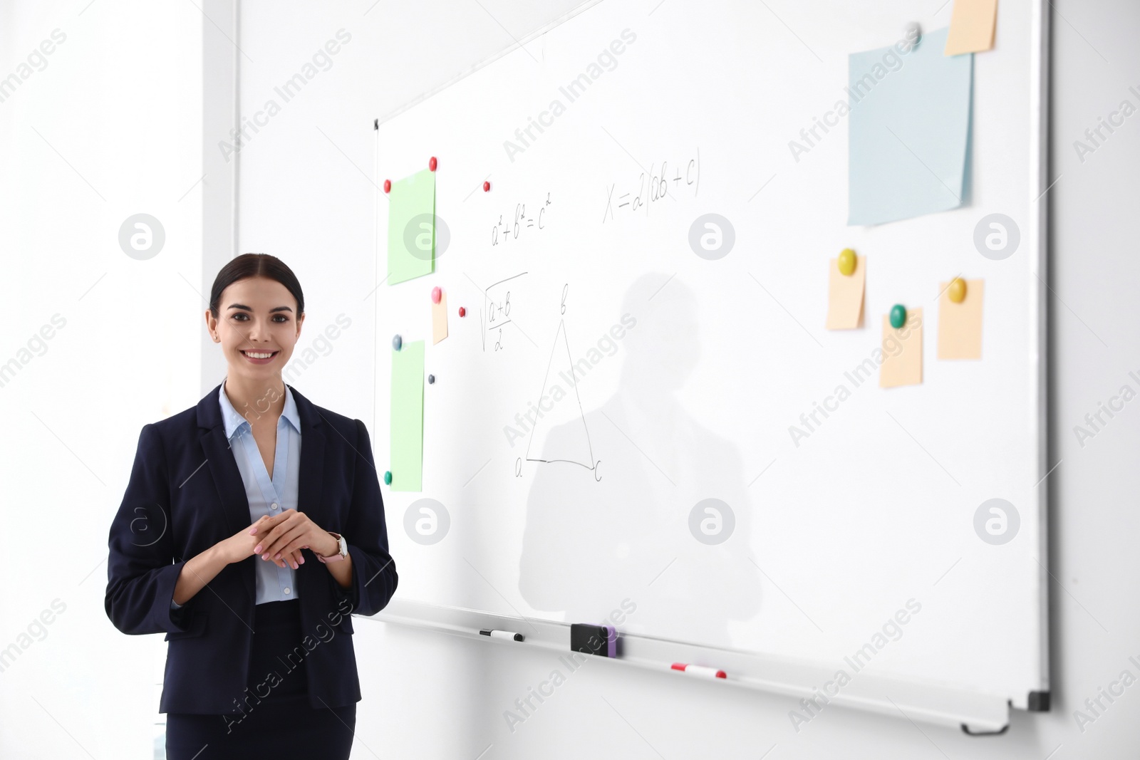 Photo of Young teacher near whiteboard in modern classroom. Space for text