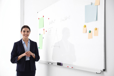 Photo of Young teacher near whiteboard in modern classroom. Space for text